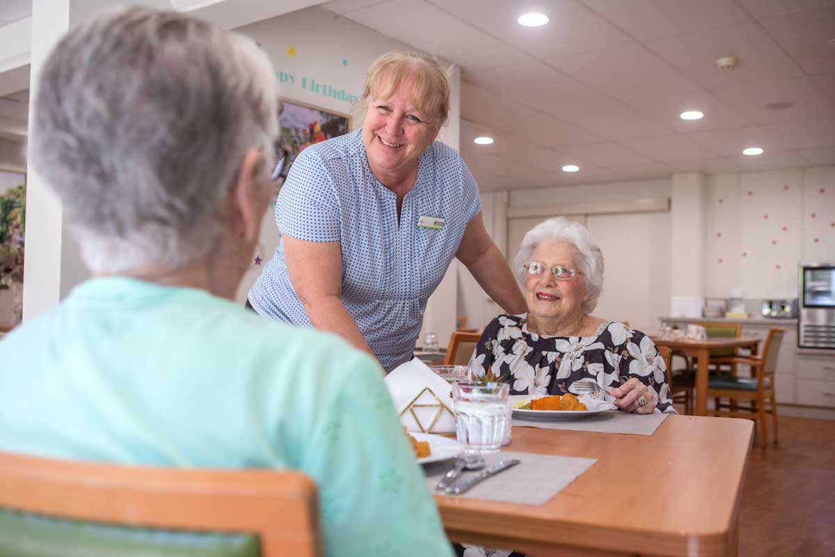 Food-Services-and-Cleaning-web Elderly residents having dinner together with food service person smiling