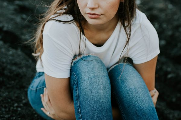 Wellbeing mental health service Woman sitting on ground with arms around knees