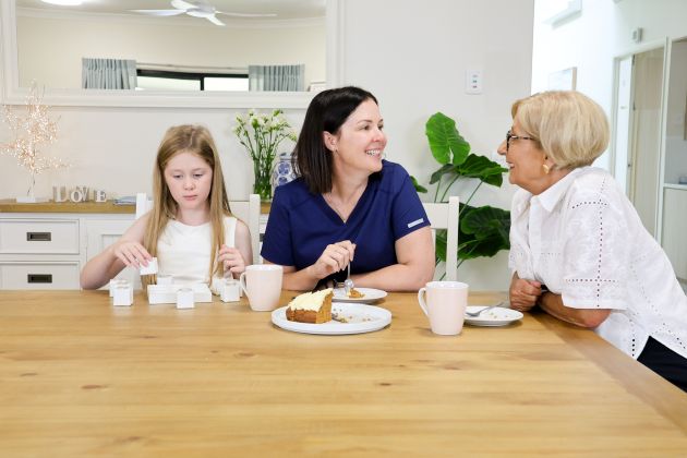 Three people at a dining table, smiling and talking