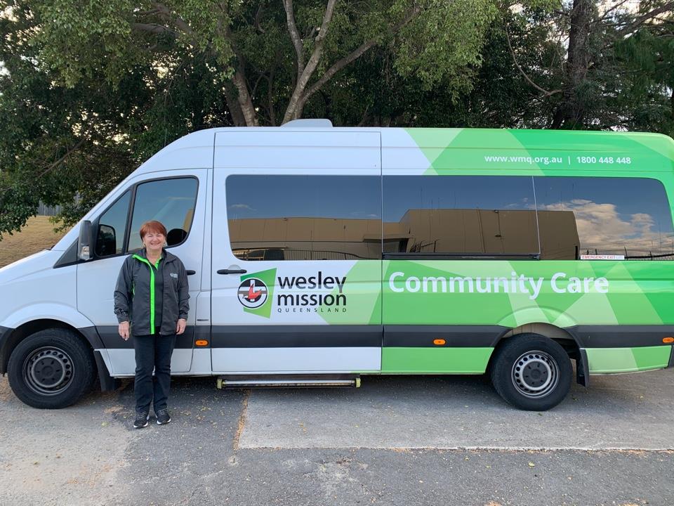 Kathy is a volunteer for Wesley Mission Queensland's Community Assisted Transport service Woman standing in front of a minibus